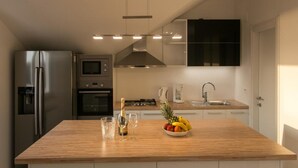 Una cocina moderna con una isla central, horno empotrado, microondas y refrigerador de acero inoxidable.