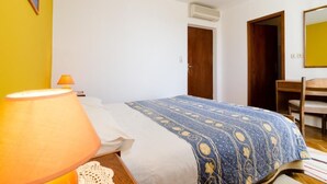 Une chambre à coucher avec un lit, une chaise, un bureau et une lampe.