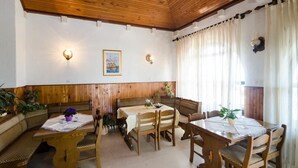 Un espace repas avec des bancs et des tables en bois, un plafond en bois et des luminaires fixés au mur.