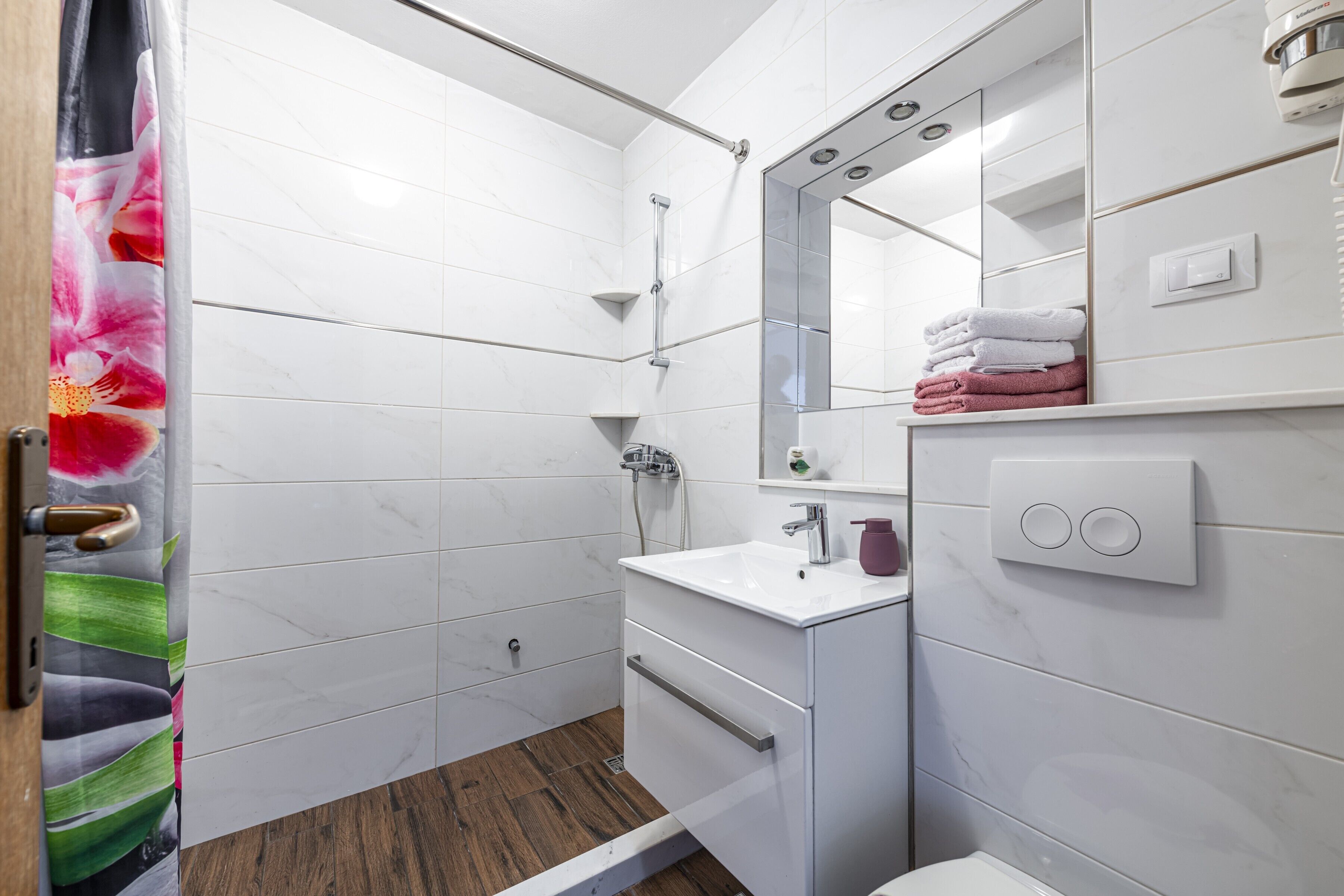 A modern bathroom with a shower, a sink, and a toilet.