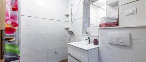 A modern bathroom with a shower, a sink, and a toilet.