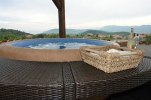 Un bain à remous avec une petite table en osier et une bouteille de champagne.