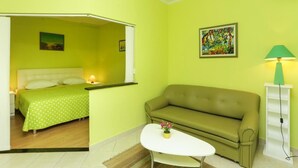 Ein Zimmer mit einem Bett, einem grünen Sofa, einem weißen Tisch und einem Bild an der Wand.