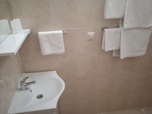 A bathroom with a sink, mirror, and multiple white towels hanging on a rack.