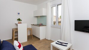 Un espacio habitable compacto con kitchenette, comedor, sofá y televisor.