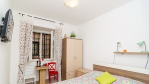 Une chambre à coucher comprenant un lit, un bureau, une chaise, une armoire et un téléviseur.