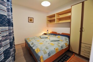 Un dormitorio con cama, armario, mesita de noche y un cuadro en la pared.