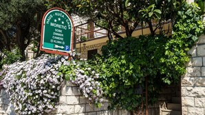 Señal con indicaciones hacia un hotel llamado 'Haus - Kuca - Casa Moretic Sobe Zimmer Klima' y un símbolo de estacionamiento.