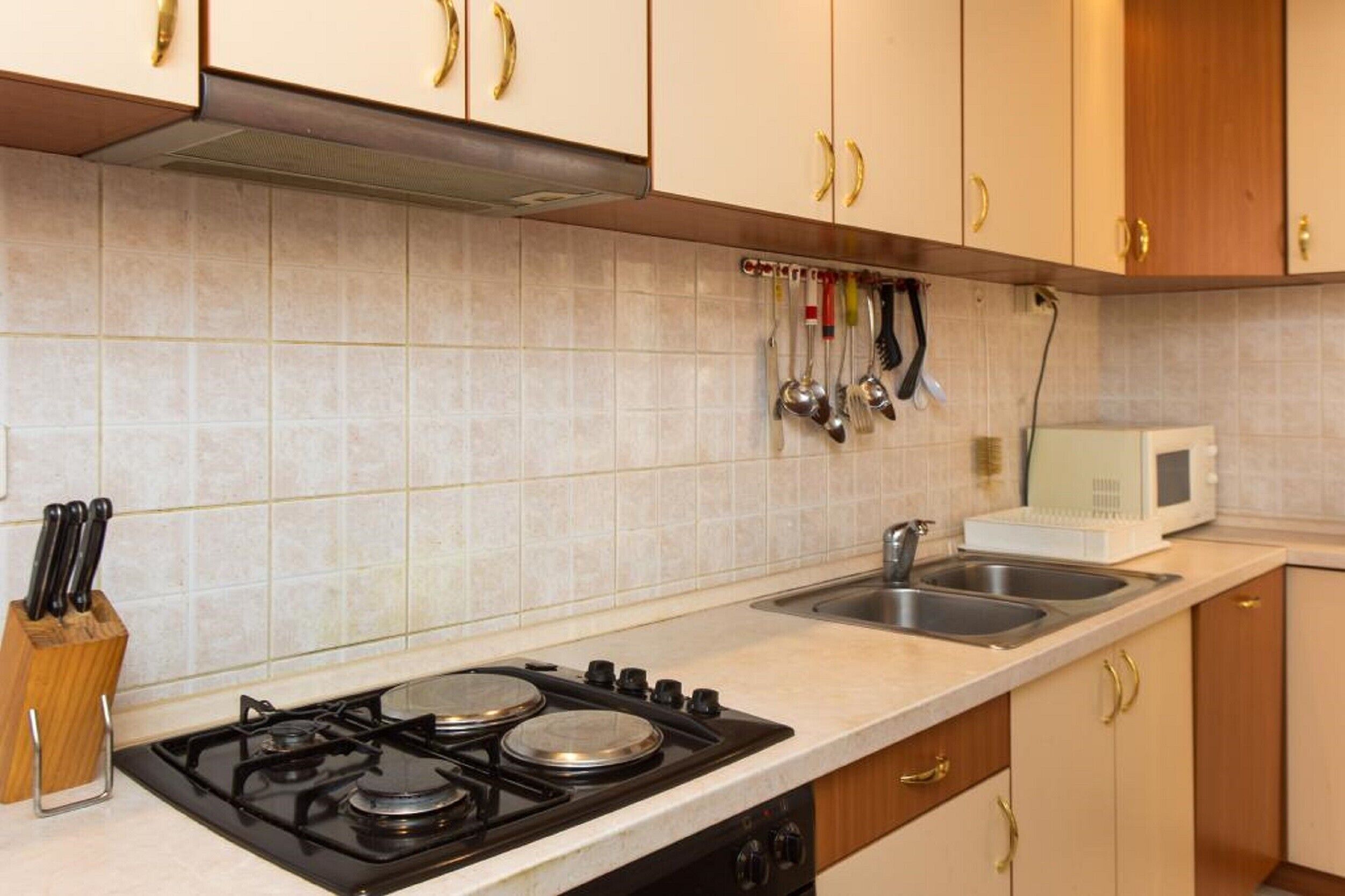 Una cocina con estufa a gas, dos fregaderos y microondas.