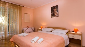 Una camera da letto con un letto grande, due comodini, un tavolino e un quadro appeso al muro, oltre a una finestra con tende.