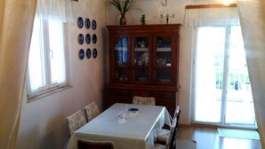 A dining room with a table, chairs, a cabinet with glass doors, and a window with curtains. - Apartment Agata - Two Bedroom Apartment with Terrace and Sea View (ST) (Splitska)