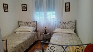 A room with two single beds, a small table with a lamp, and a window with sheer curtains. - Apartment Agata - Two Bedroom Apartment with Terrace and Sea View (ST) (Splitska)