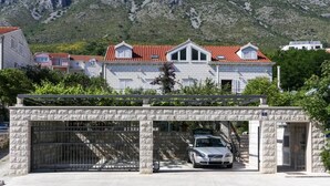 Ein modernes Gebäude mit einer Stein-Fassade, einem roten Ziegeldach und einem Auto auf der Auffahrt.