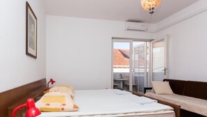 Un dormitorio con cama de madera, lámpara roja, sofá y ventana con vista a edificios.