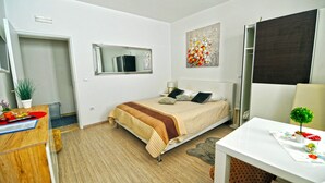 Ein Schlafzimmer mit Bett, Schreibtisch, Stuhl, Spiegel und einem Wandbild.