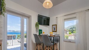 Ein Essbereich mit Tisch, Stühlen, einem Fernseher und Meerblick.
