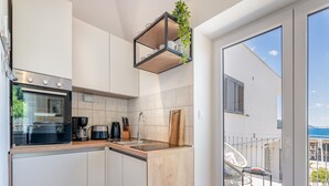 Eine moderne Küche mit Einbauofen, Kaffeemaschine und einer Wandregal mit Pflanzen.