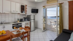 Cozinha compacta com área de jantar e varanda com vista.