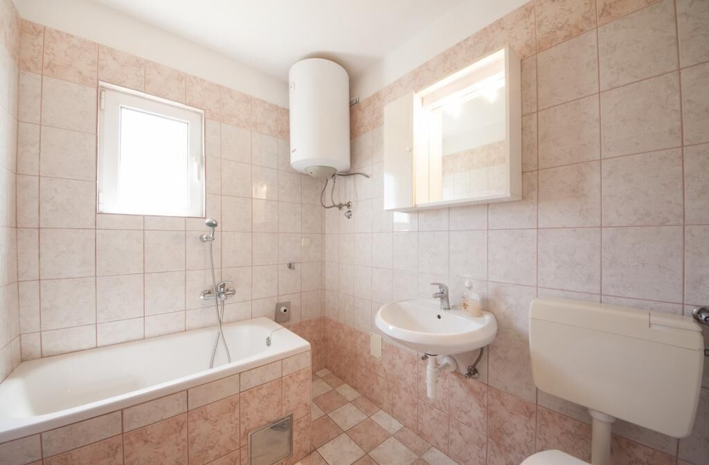 Ein Badezimmer mit Badewanne, Waschbecken, Toilette und einem Fenster.