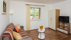 Un salon moderne avec un canapé, un meuble pour la télévision, un buffet et une fenêtre avec des rideaux.