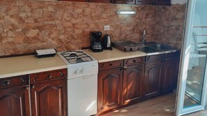 A kitchen with dark wooden cabinets, a stone backsplash, a gas stove, a coffee maker, and a dishwasher. - Guest House Oreb - Comfort Double Room (Kolocep)