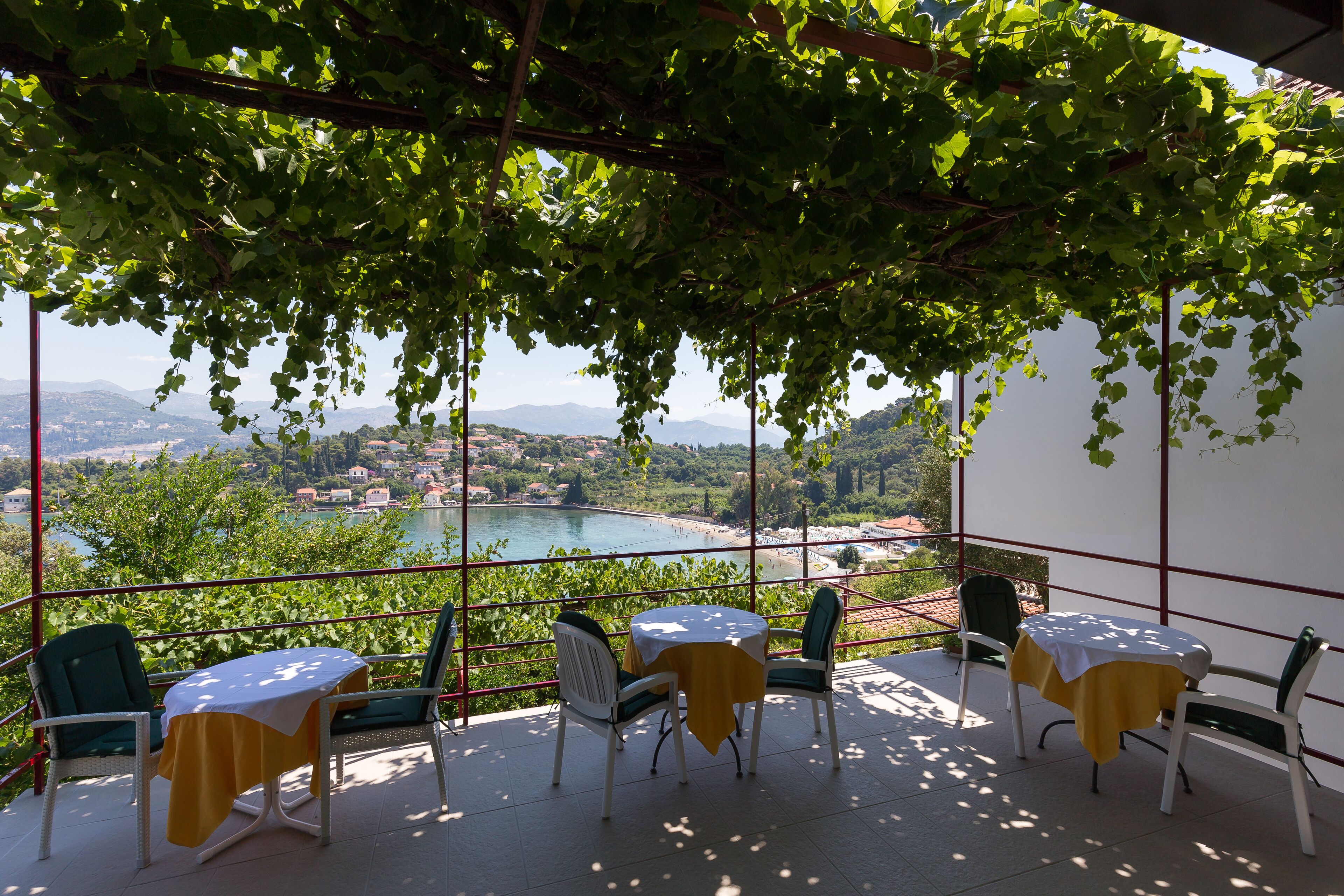 A terrace with a table and chairs, overlooking a scenic view of a lake and mountains.