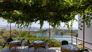 A terrace with a table and chairs, overlooking a lake and mountains. - Guest House Oreb - Comfort Double Room (Kolocep)
