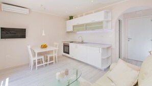 A modern kitchen with white cabinets, a built-in oven, and a glass-top dining table.