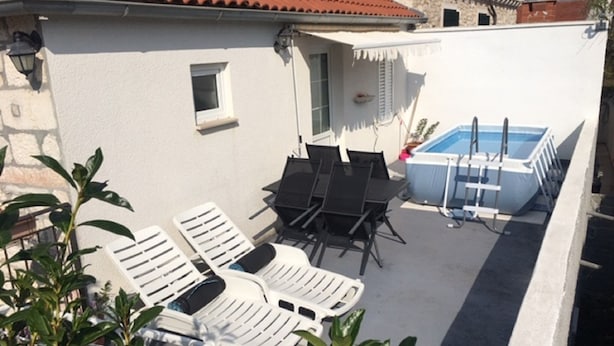 A patio with lounge chairs, a table, and a swimming pool. - Apartment Glavica- Two Bedroom Apartment with Terrace (Supetar)