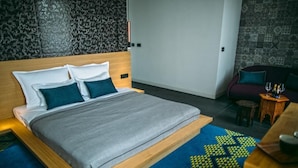 A modern bedroom with a large bed, a wooden headboard, a patterned carpet, and a small seating area with a table. - Rooms Lejletul - Comfort Double Room with Square View (Bedr) (Split)