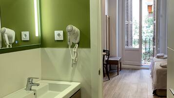 Un bagno moderno con una parete verde, un lavandino bianco e due asciugacapelli fissati al muro.