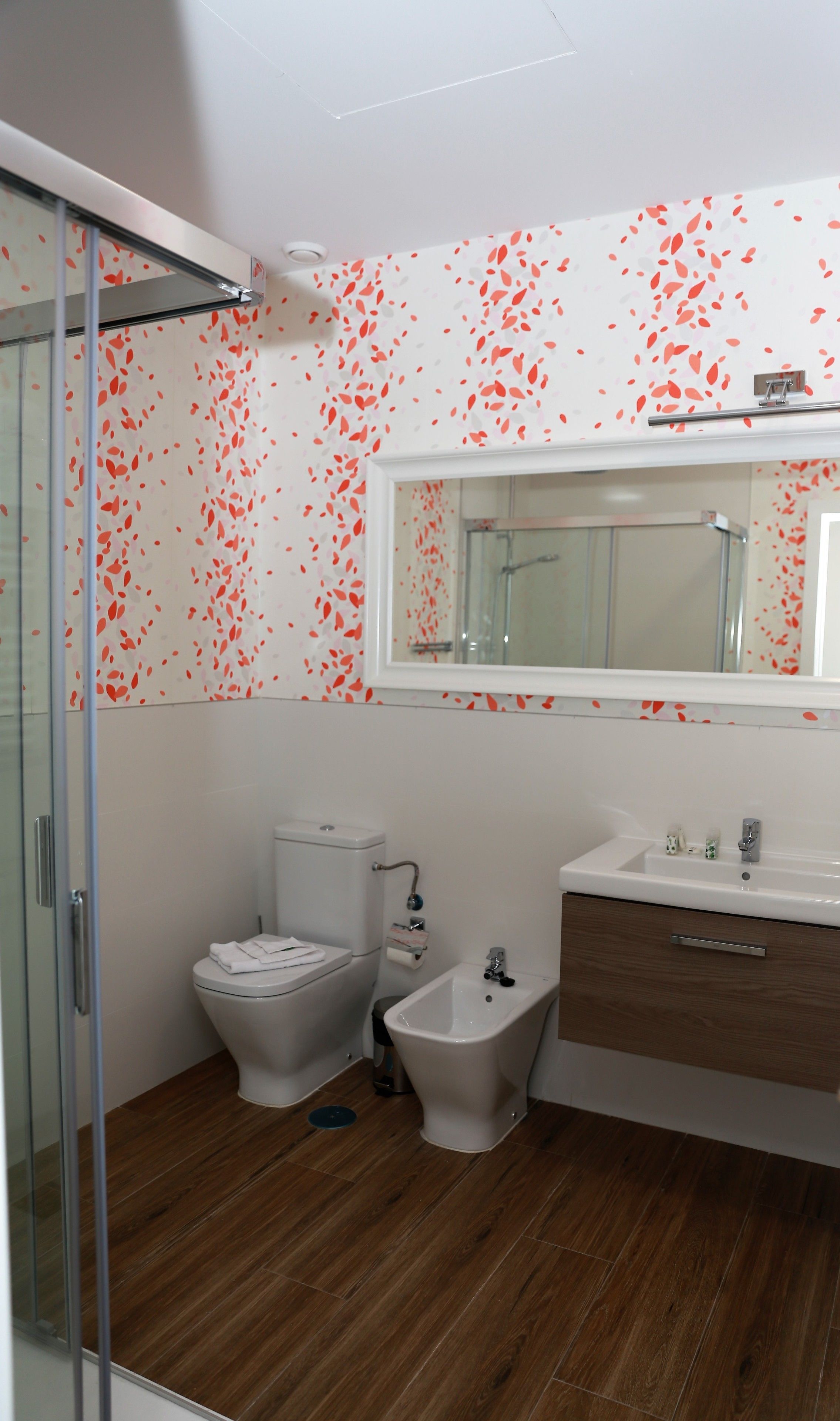 Une salle de bain équipée de toilettes, d’un bidet et d’une douche à parois de verre.