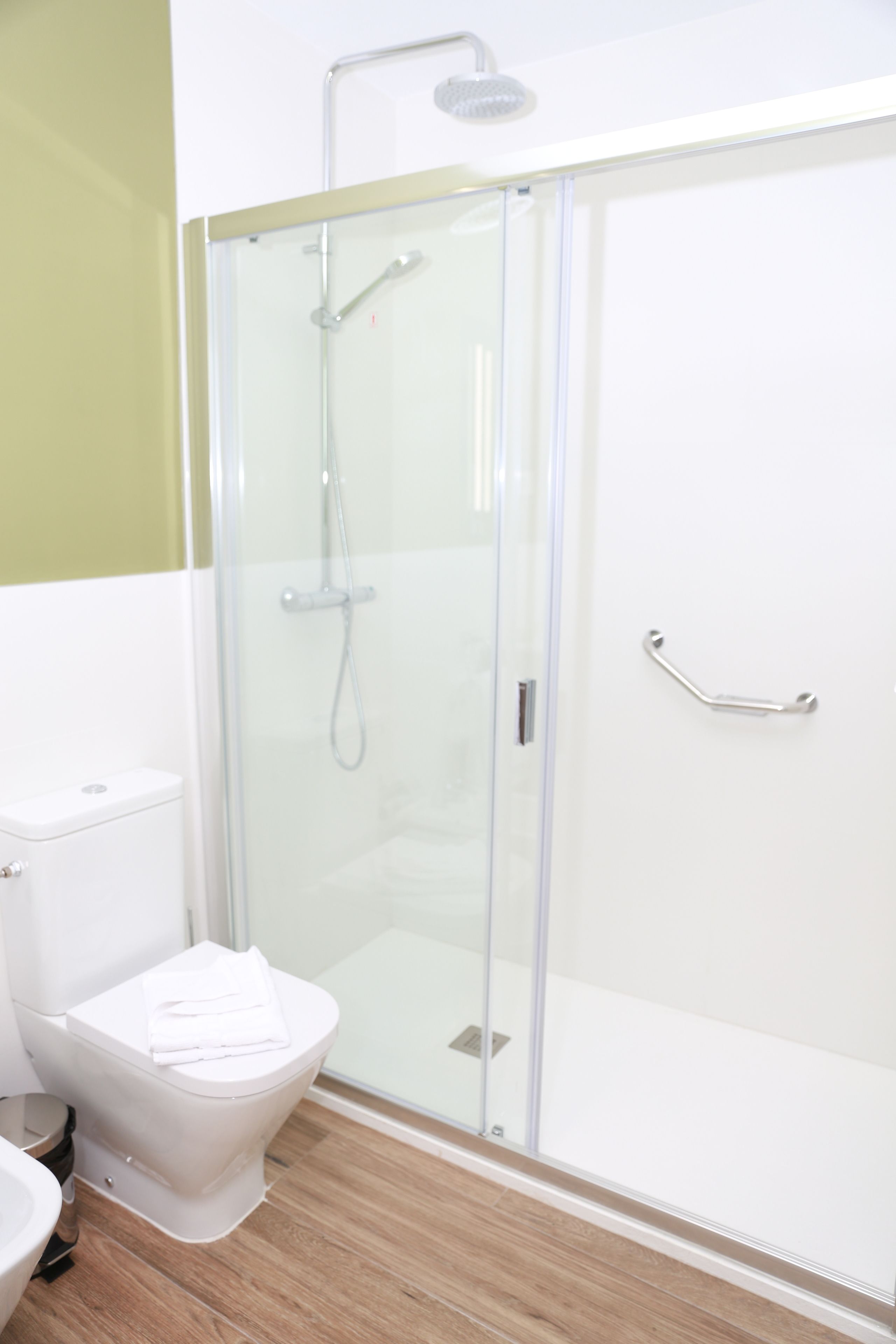 A bathroom with a glass-enclosed shower, a toilet, and a sink.