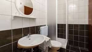 Ein Badezimmer mit weißem Waschbecken, Toilette, Duschkabine und Spiegel an der Wand.