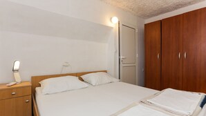 A bedroom with a wooden bed, a nightstand, a wardrobe, and a bedside lamp.