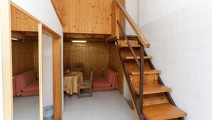 A wooden interior with a staircase, a sofa, and a small dining area.