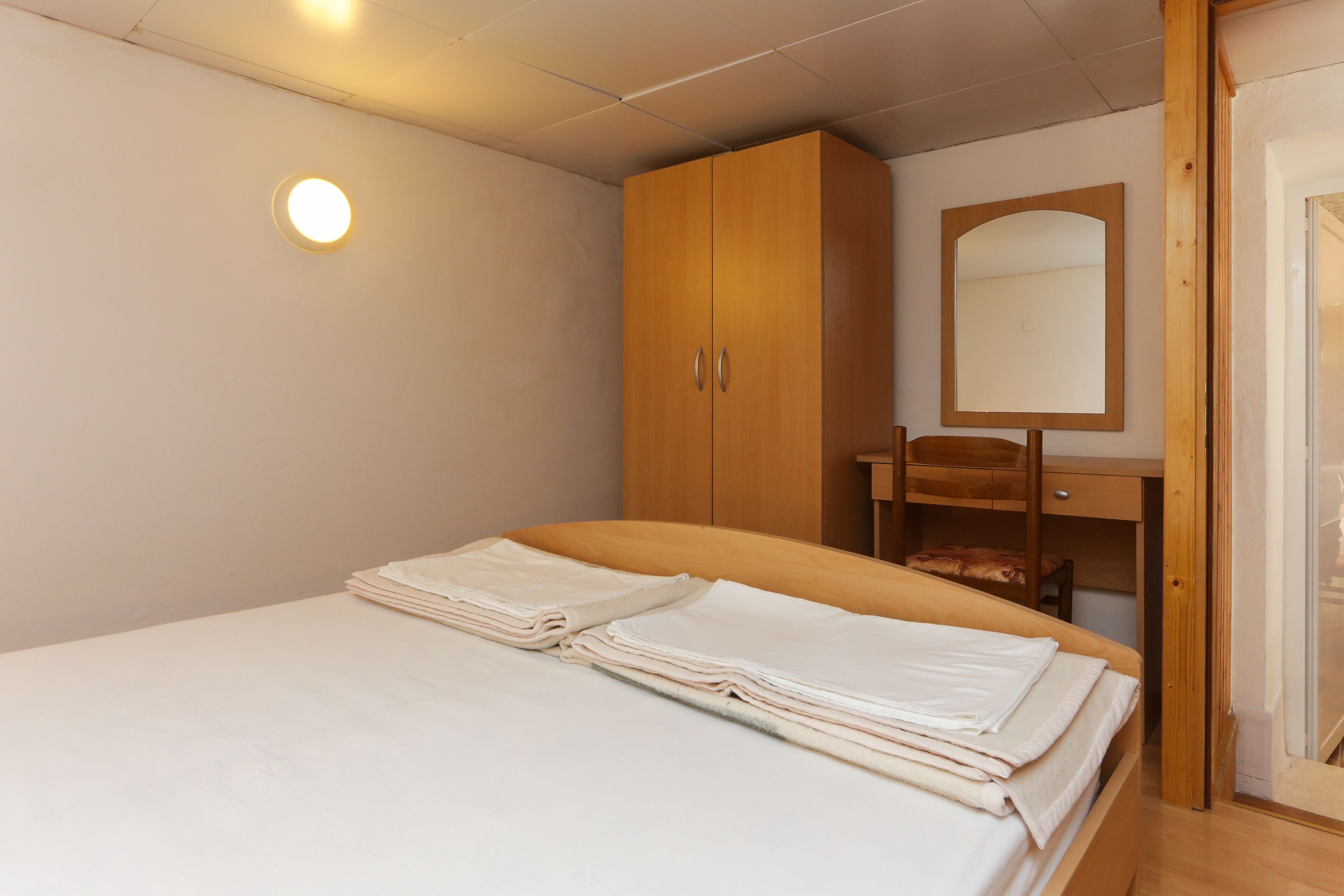 A bedroom with a bed, wooden wardrobe, and a mirror.