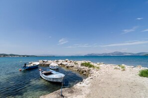 Un lac paisible, avec des bateaux amarrés au bord et une côte rocheuse en arrière-plan.