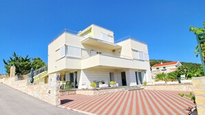 A two-story house with a balcony, a garage, and a paved driveway. - Apartments Gusti - One Bedroom Apartment with Terrace and Sea View (Drace)
