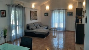 A spacious living area with a large sofa, a dining table, and a small side table. - Apartment Bruna - Two Bedroom Apartment with Terrace (Mirca)