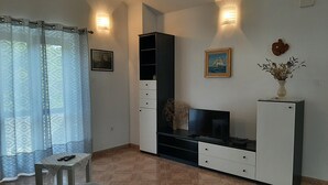 A living room with a sofa, TV stand, and a small table with remotes. - Apartment Bruna - Two Bedroom Apartment with Terrace (Mirca)