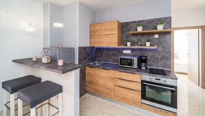 Una cocina moderna con horno empotrado, microondas y taburetes de bar.