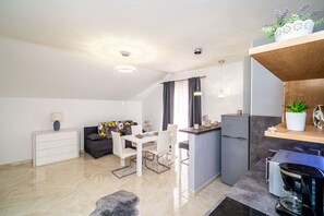 A modern kitchen with a dining area, a small bar, and a living space with a sofa and a coffee table.
