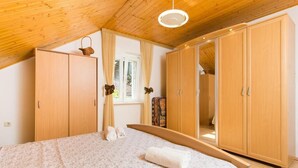 Quarto com cama, guarda-roupa de madeira e janela com cortinas.