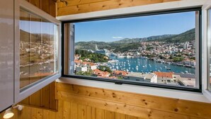 Quarto com uma grande janela com vista para uma marina com barcos e uma cidade.