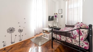 Un dormitorio con una cama, una mesita de noche, un televisor y una estantería.