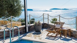 Zona de piscina con vistas al mar, una tumbona, una planta en maceta y una ducha.