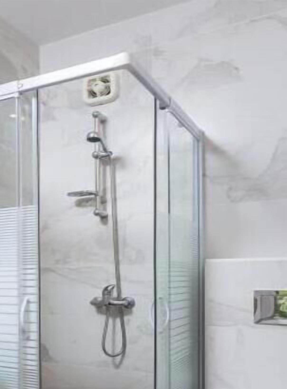 A modern bathroom with a glass-enclosed shower, a sink, and a toilet.
