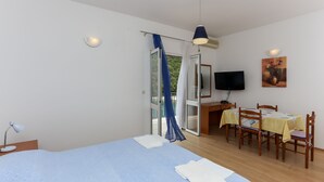 A bedroom with a bed, a desk, a chair, a TV, and a dining table. - Apartments Posta - Studio with Balcony and Sea View (Saplunara)