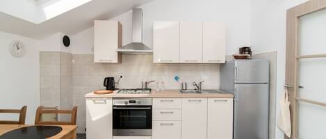 A modern kitchen with a skylight, a built-in oven, and a refrigerator.